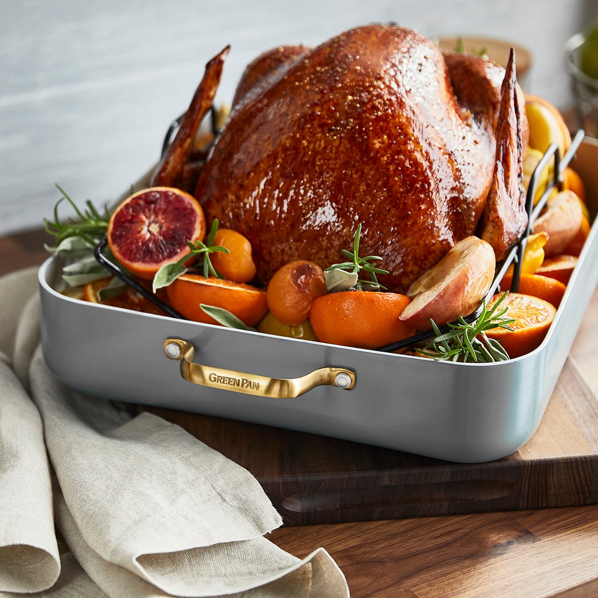 Front view of Reserve Collection Roaster with Rack showcasing black charcoal finish and turkey on a wooden table