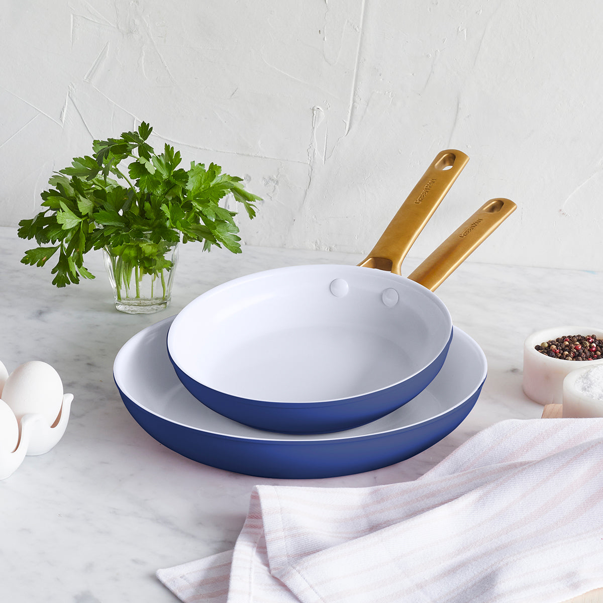 Front view of Reserve Collection 2-Piece Fry Pan Set showing two dark blue pans with white interiors on a marble counter