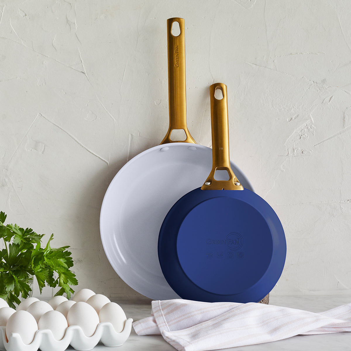 Overhead view of Reserve Collection 2-Piece Fry Pan Set in Dark Blue showcasing two pans with gold-tone handles on a textured kitchen surface