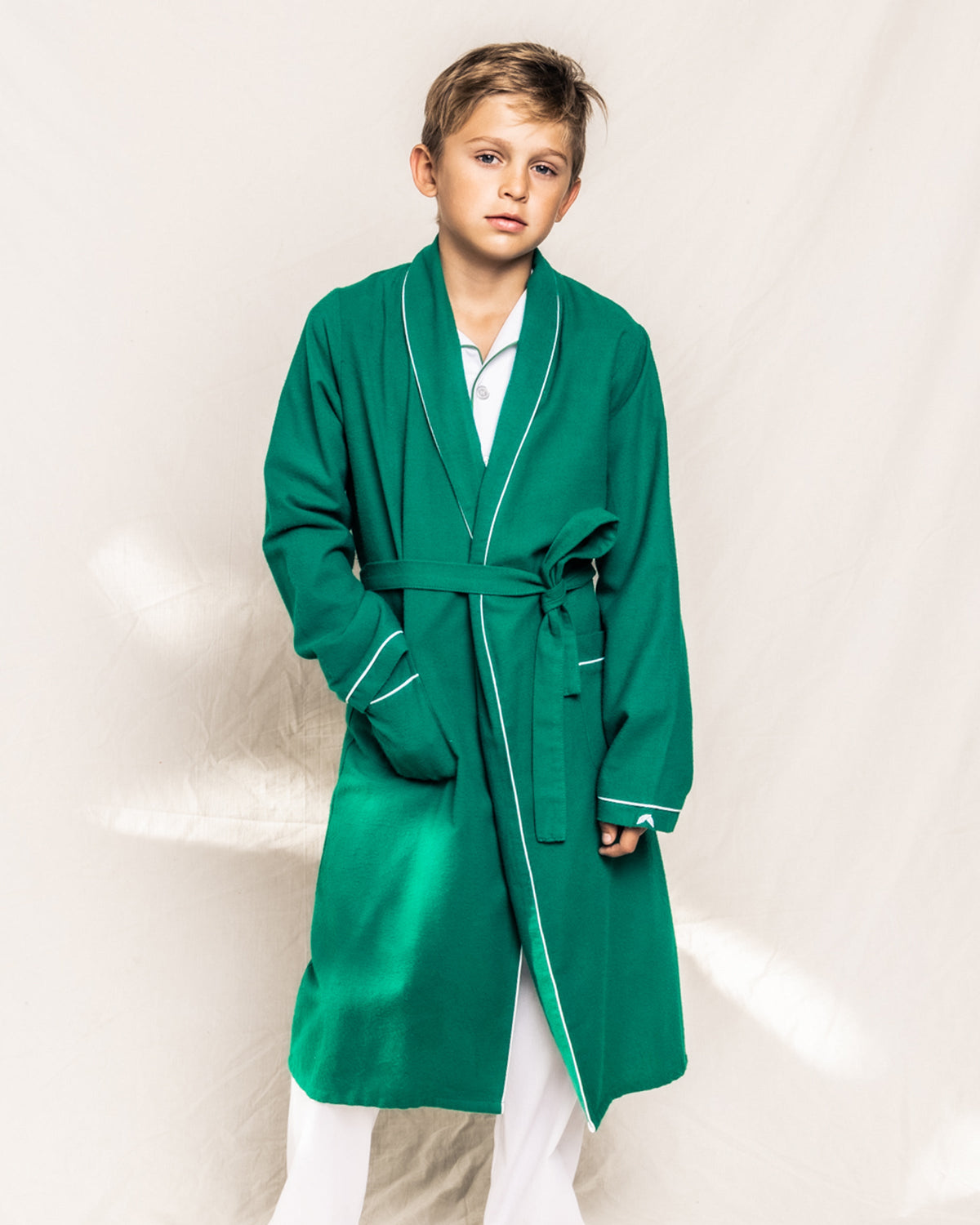Front view of children’s forest green flannel robe showcasing white piping and belt on a child against a white backdrop