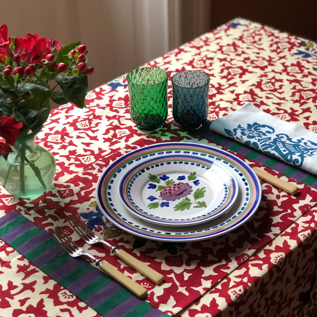 Angled view of Artichoke Dinner Plate showcasing a colorful artichoke flower design with a patterned table setting