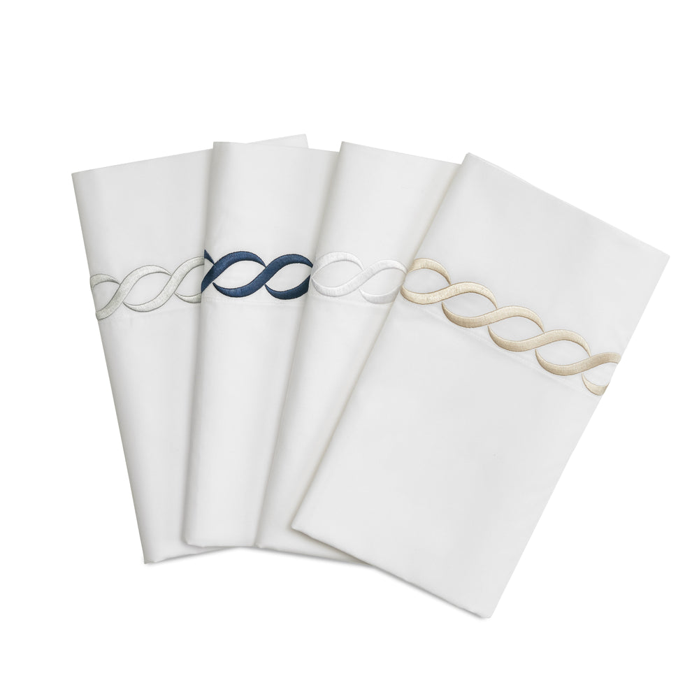 Four folded Catena Full/Queen flat sheets showcasing embroidered cable border in navy, silver, white, and taupe on a white background