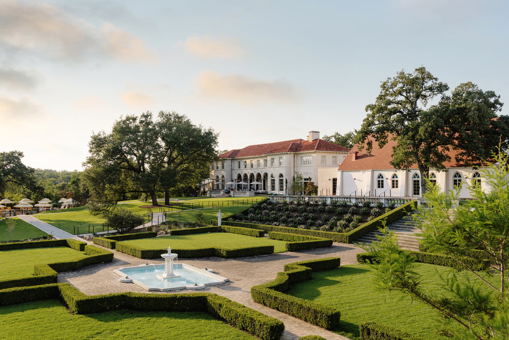 Formal hedged gardens and central fountain in front of the Mediterranean-style Commodore Perry Estate at golden hour
