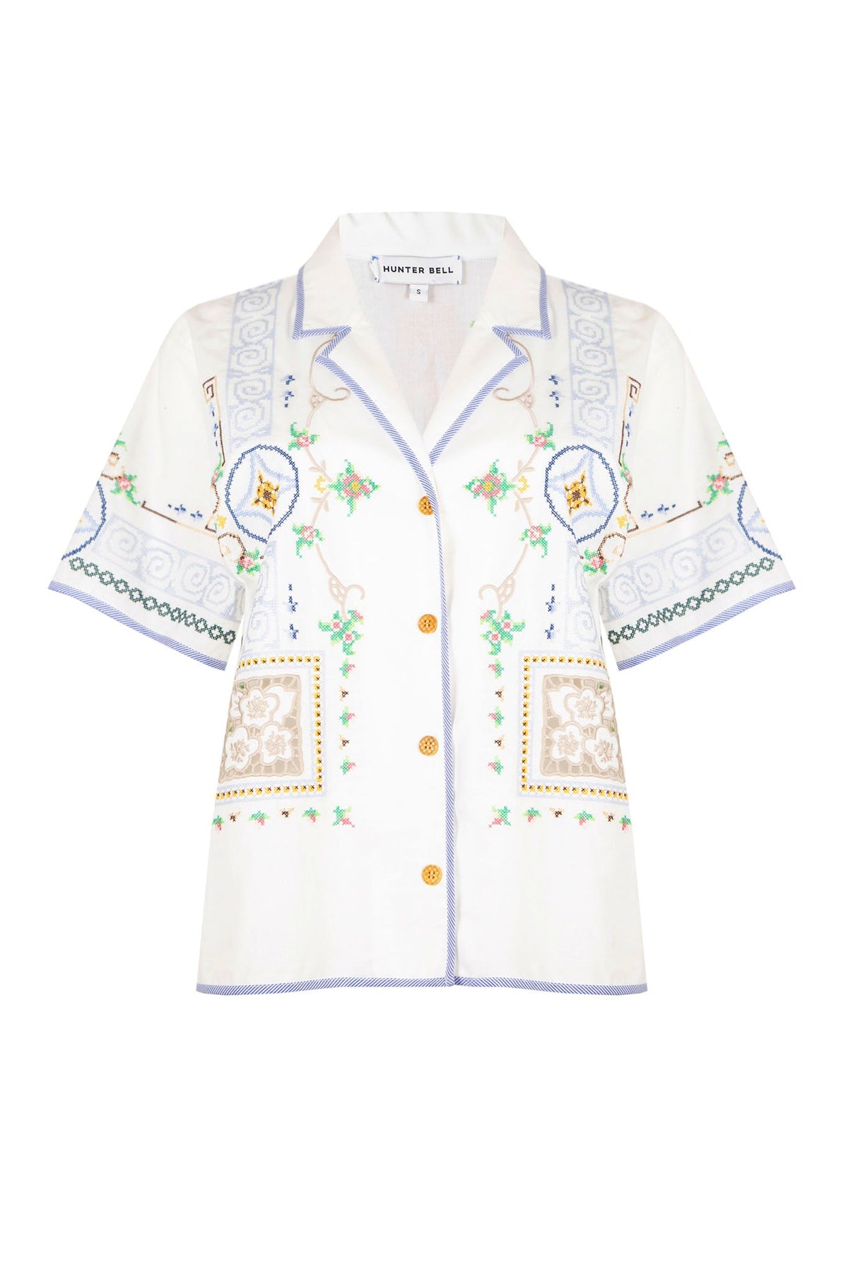 The Cora top has mosaic embroidery, eyelet cutouts, striped piping and wooden buttons.