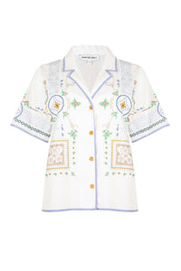 The Cora top has mosaic embroidery, eyelet cutouts, striped piping and wooden buttons.