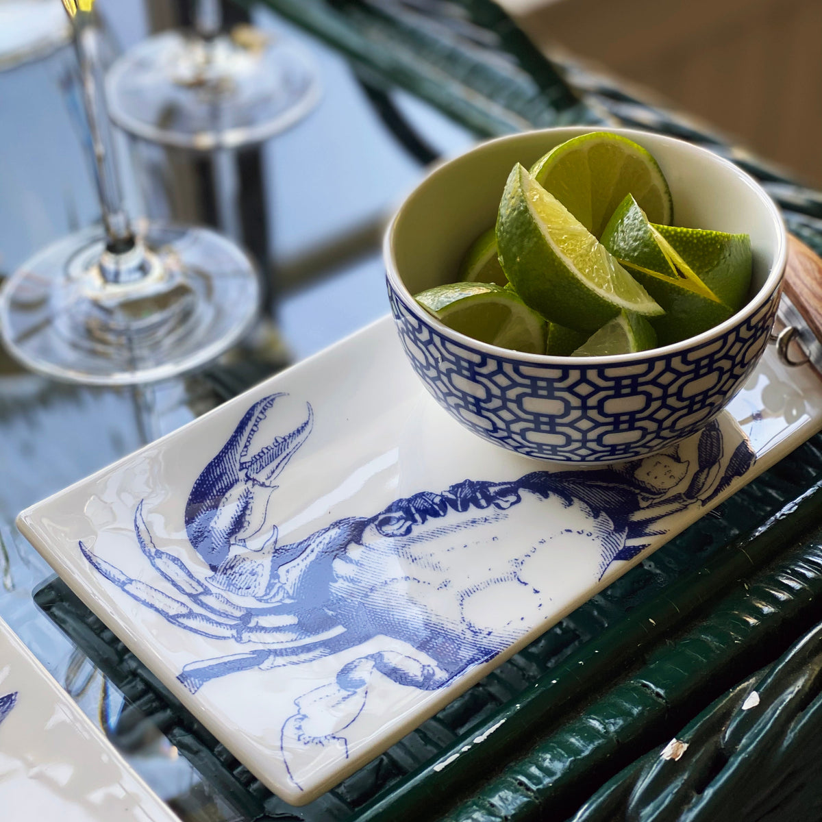 A Newport Snack Bowl filled with quartered limes. Premium, blue and white porcelain small bowl from Caskata, styled with a Crab Sushi Tray..