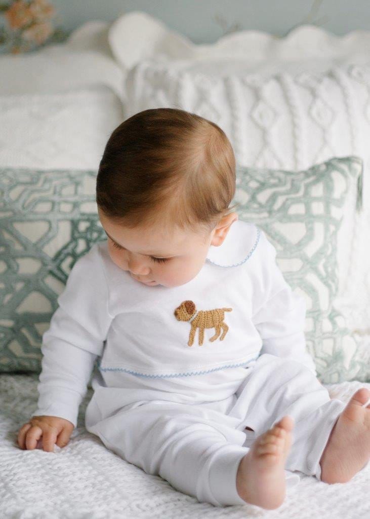 Front view of Boy Lab Crochet Playsuit on a seated baby showing white playsuit with embroidered puppy and Peter Pan collar on a patterned pillow background