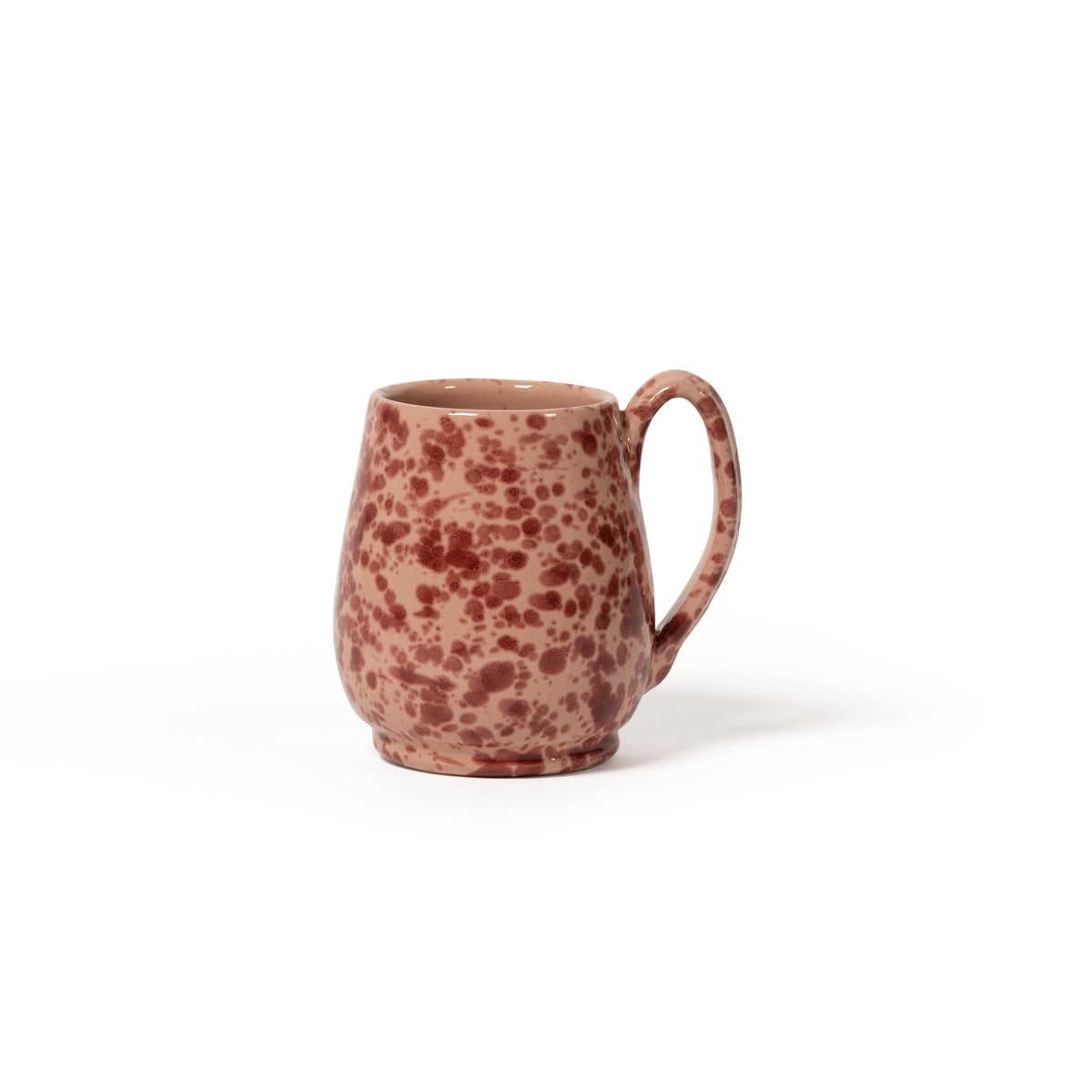 Front view of Splatter Mug showing pink ceramic with red splatter glaze and handle on white background