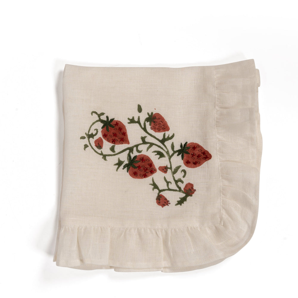 Top view of folded Fraises des Bois linen napkin showcasing hand-blocked strawberry print and ruffled edge on white background