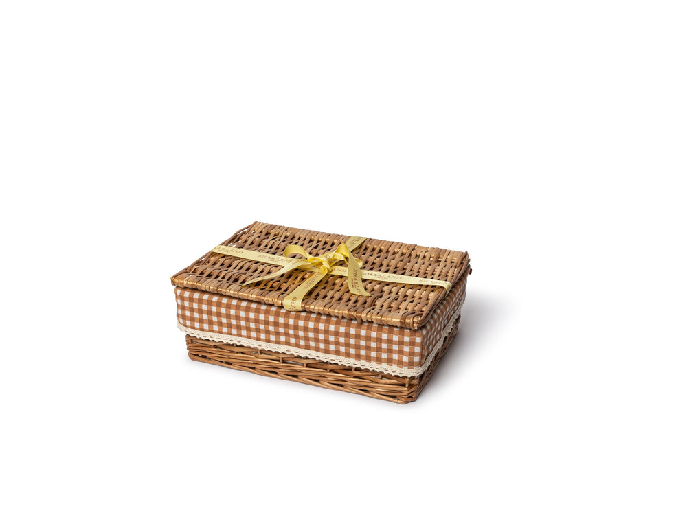 Angled view of The Chic Hamper showcasing woven wicker construction, brown gingham lining, lace trim, and yellow ribbon on a white background