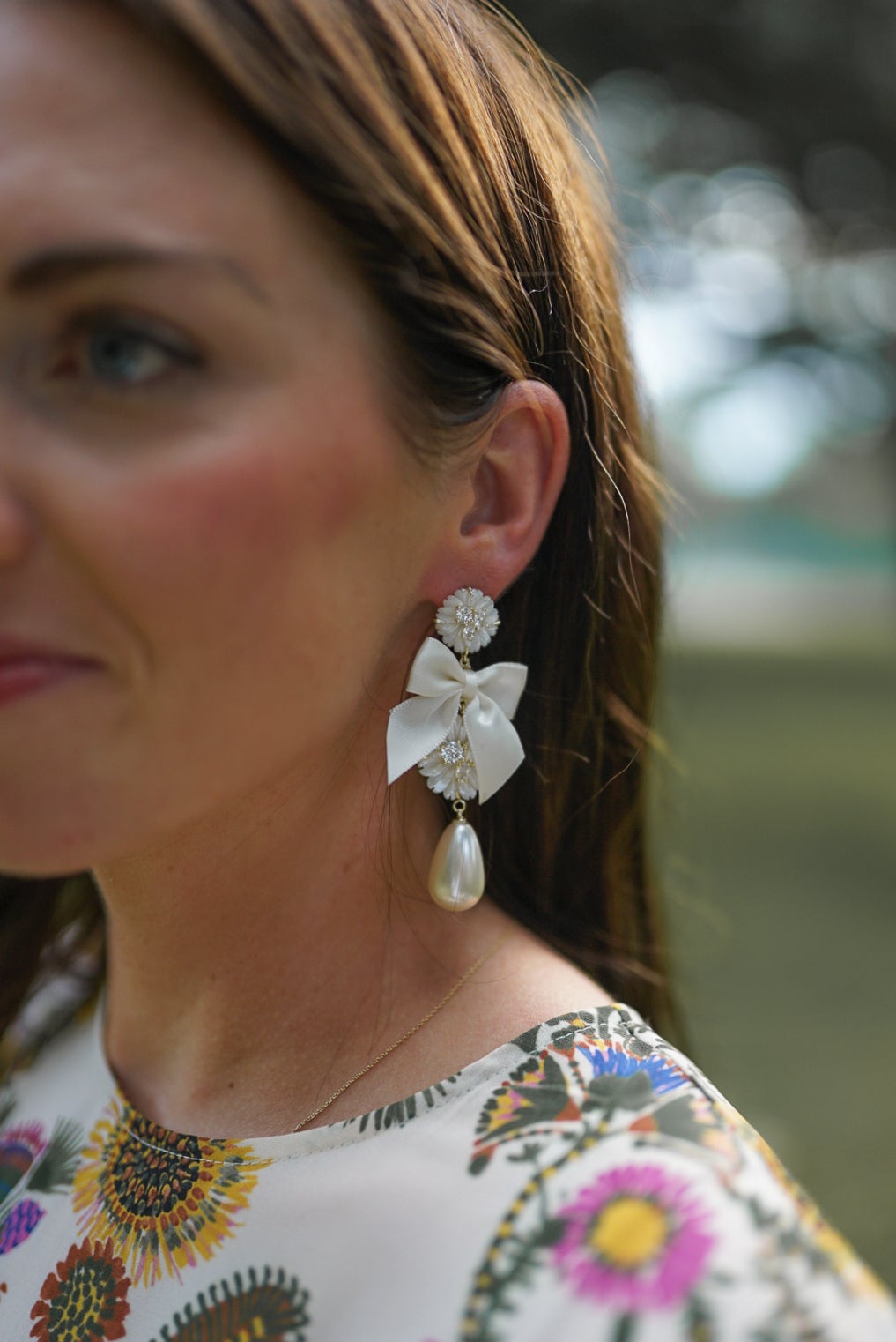Close-up of Embellished Mother of Pearl and Ivory Bow Earrings showcasing the ivory bow and pearl drop with a model outdoors