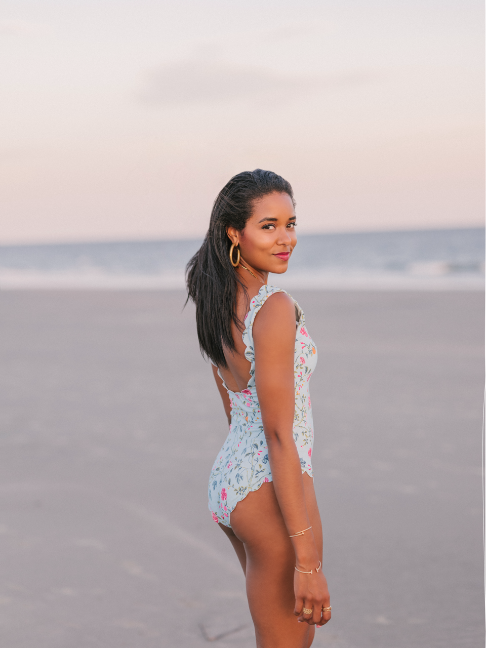 Rear three-quarter view of Palm Springs Maillot showcasing its blue floral print, lower back, and full coverage with beach background