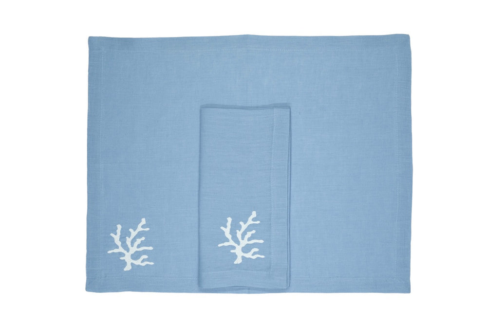Top view of Coral Collection linen placemat and napkin in mavi showcasing white coral embroidery on white background