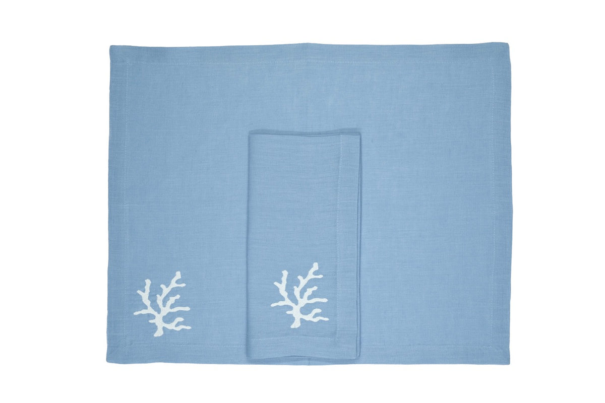Top view of Coral Collection linen placemat and napkin in mavi showcasing white coral embroidery on white background