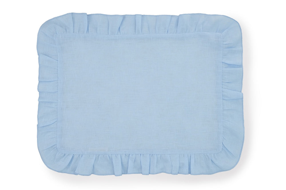 Top-down view of a pastel blue Ruffles Mavi linen placemat showcasing decorative ruffled edges on white background