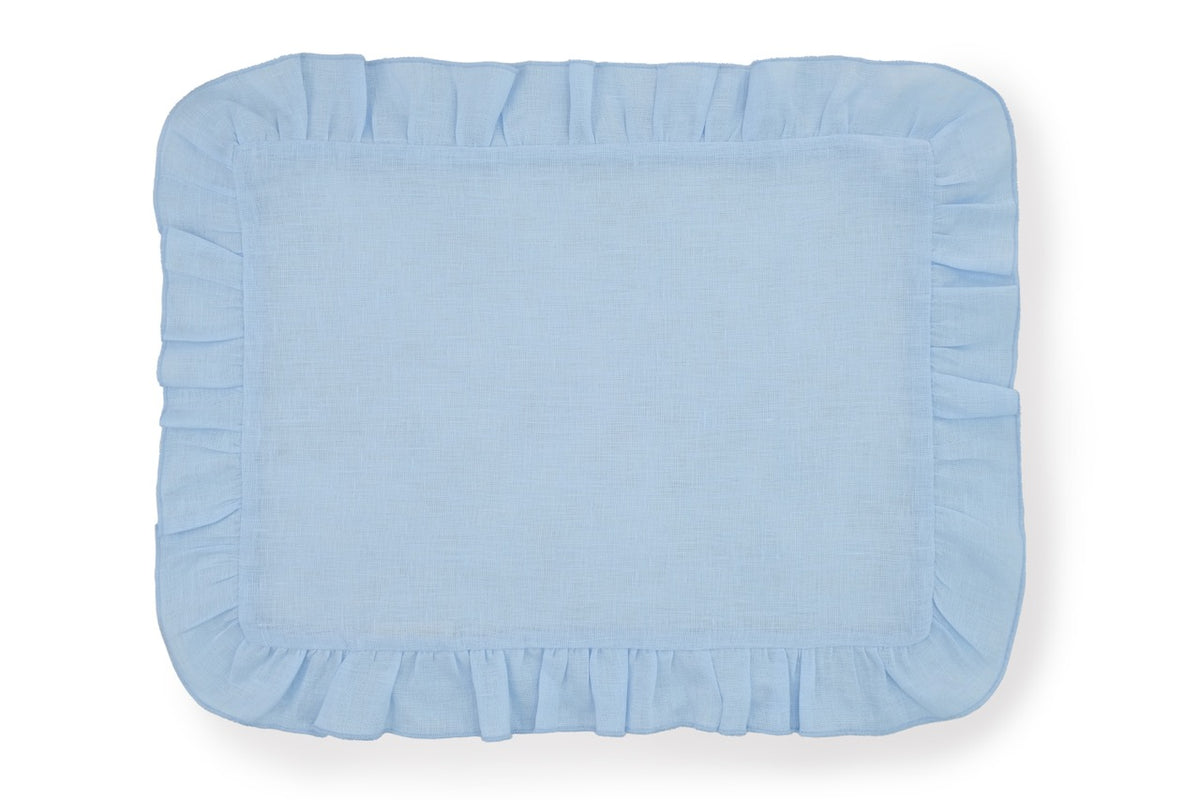 Top-down view of a pastel blue Ruffles Mavi linen placemat showcasing decorative ruffled edges on white background