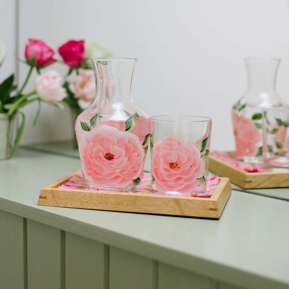 Front view of Peony Carafe And Tumbler showcasing pink peony flowers with a wooden tray and floral background