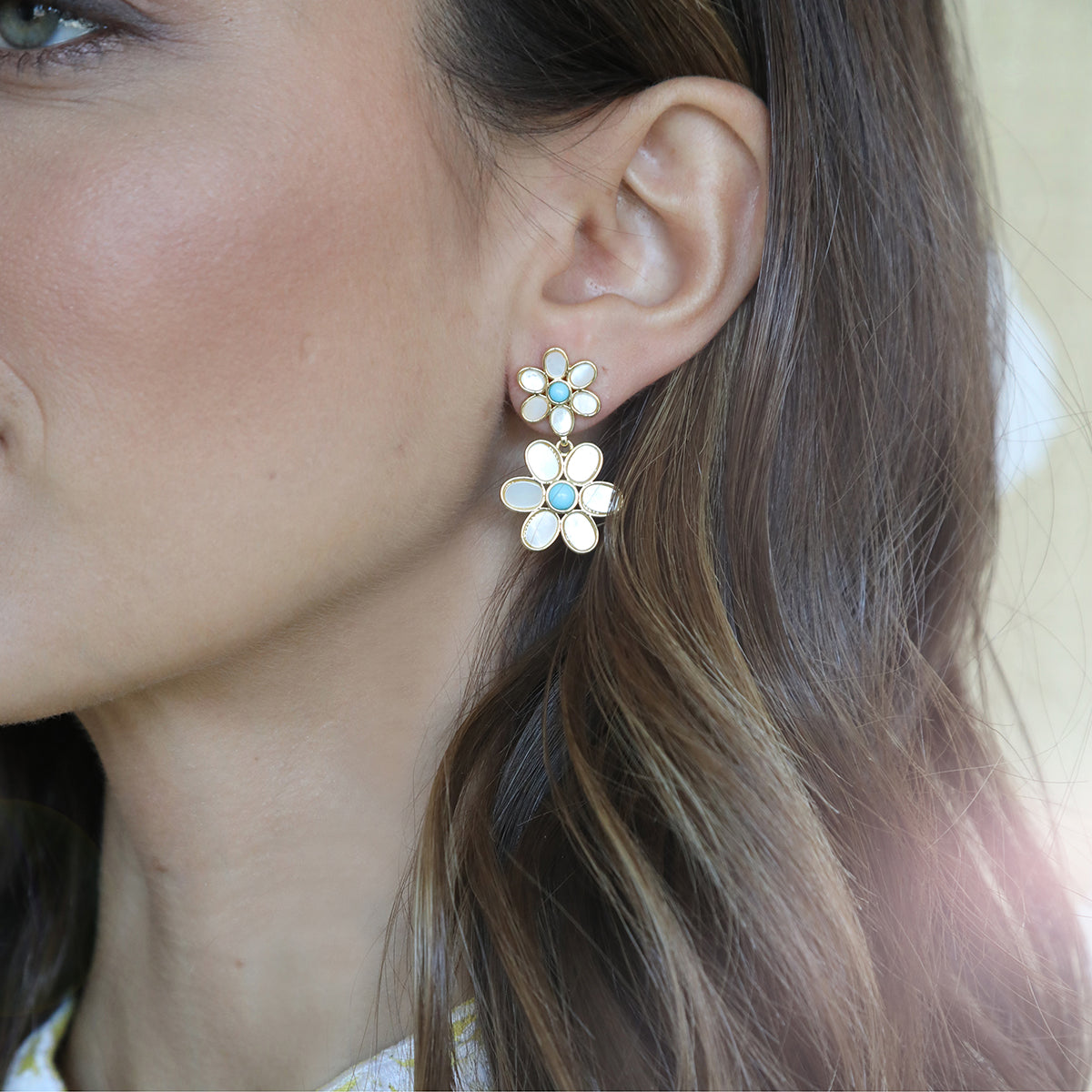Side view of Daisy Double in Turquoise showcasing mother of pearl petals and turquoise cabs with brown hair in the background