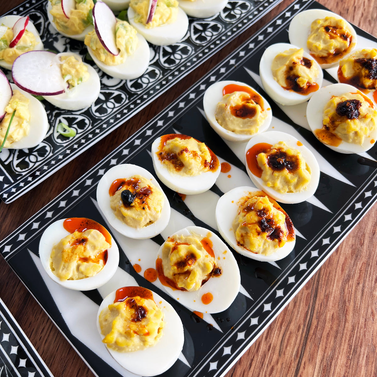 Top view of Marrakech Sushi Tray Large showcasing its black and white Art Deco pattern with deviled eggs on a wooden table