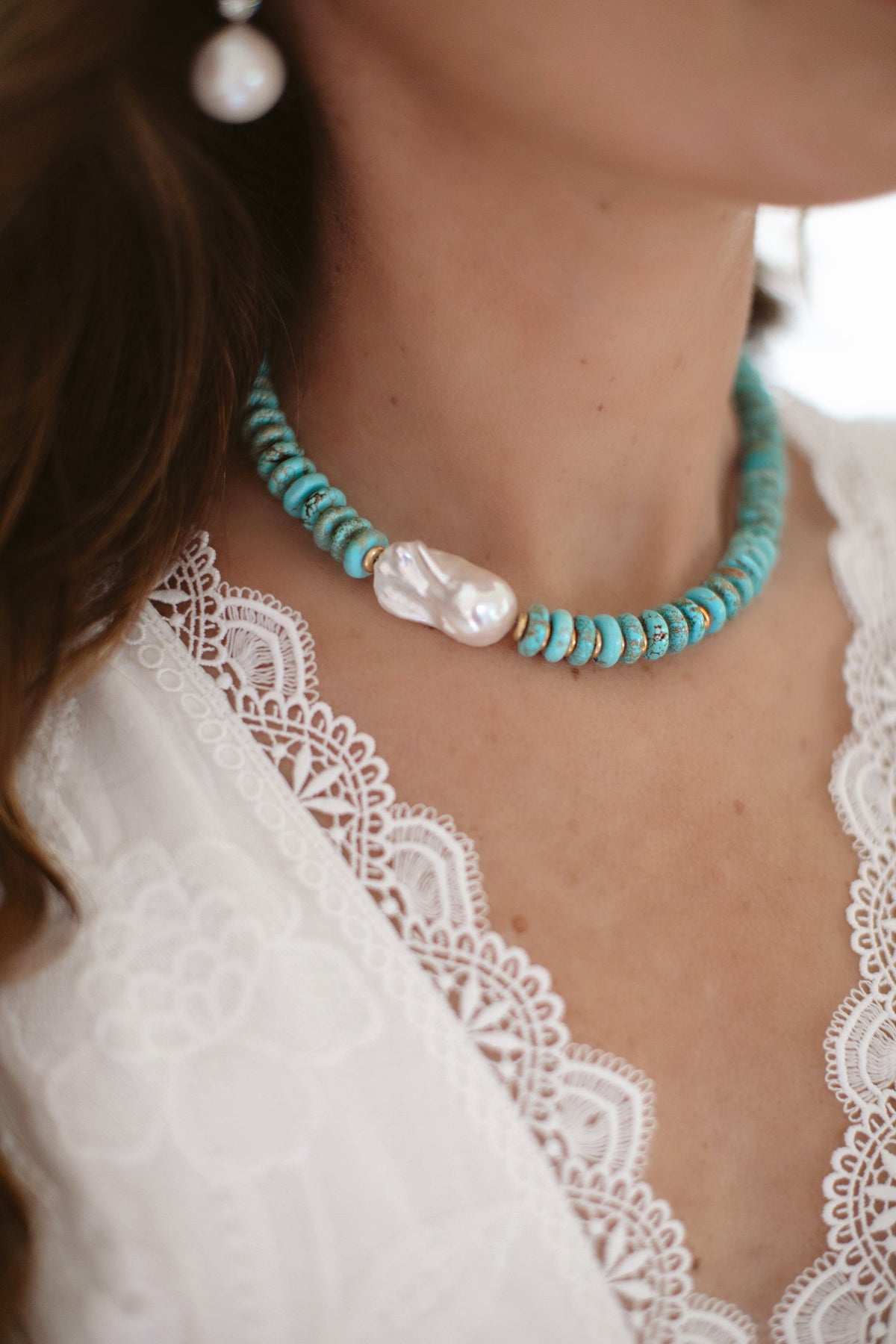 Close-up of Dune Necklace on model showcasing turquoise rondelle beads and a large baroque freshwater pearl against a white lace top