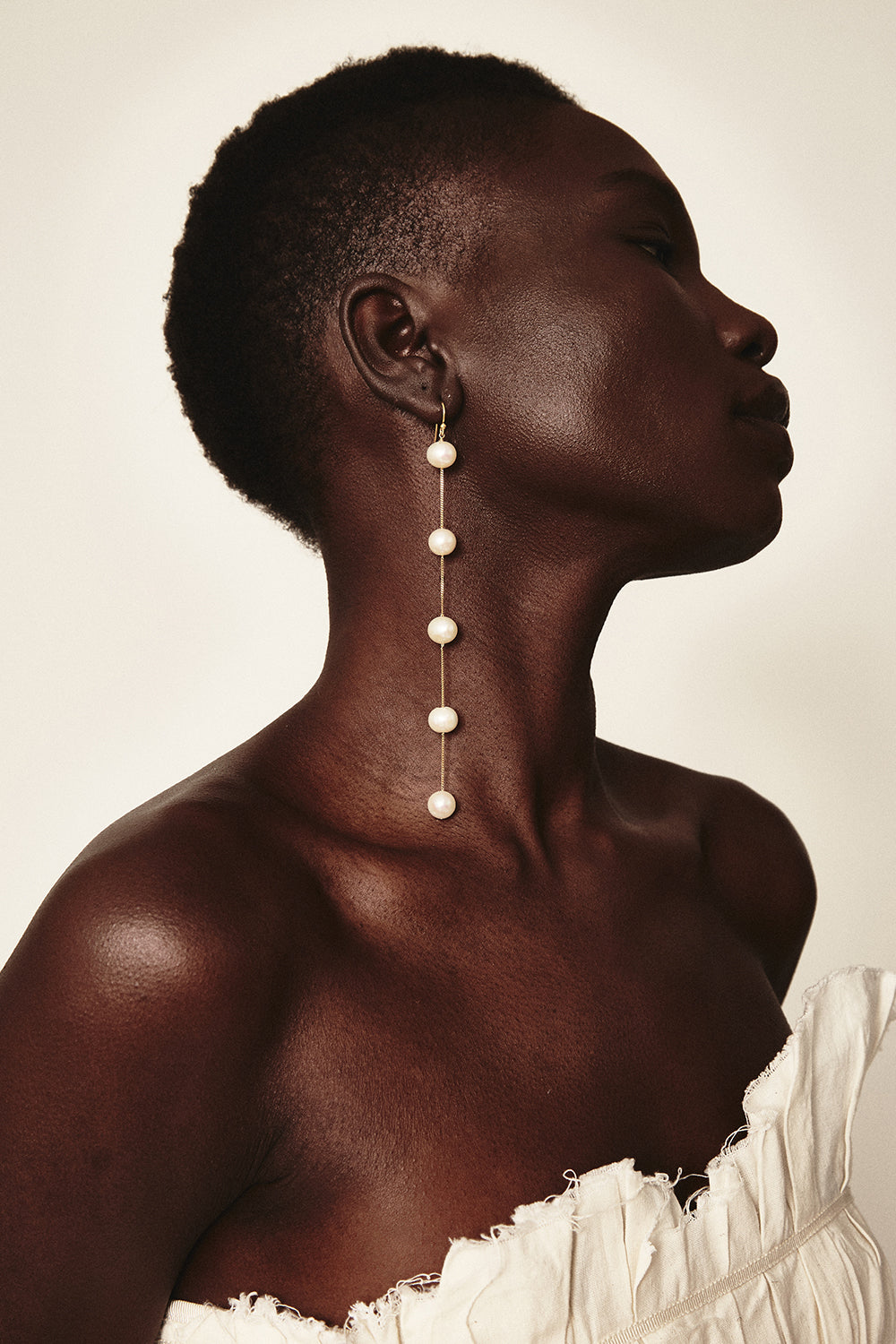 Side view of White Pearl Duster Earrings showcasing five white freshwater pearls on a model against a neutral background