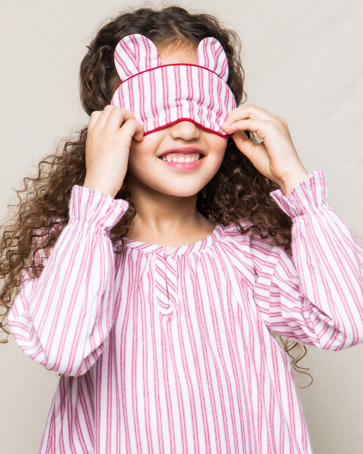 Front view of Children’s Antique Red Ticking Bear-y Sweet Eye Mask showcasing bear ears and red stripes on a smiling child