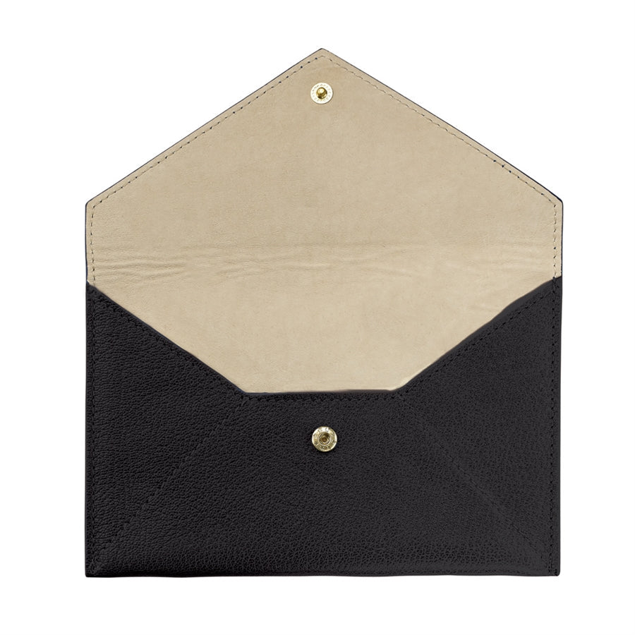Open view of medium envelope in goatskin leather showing black exterior, beige interior and gold snap closure on white background