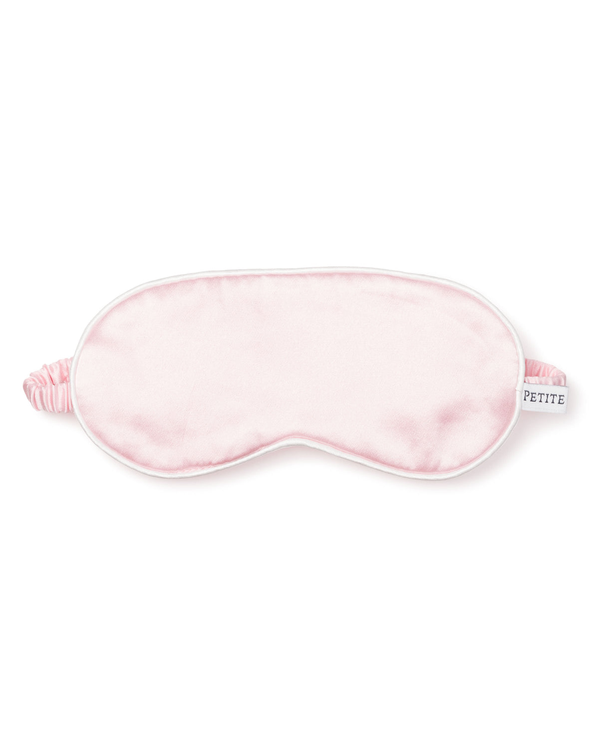 Front view of children’s pink silk eye mask showing white piped edge, elasticized back strap, and Petite tag on white background