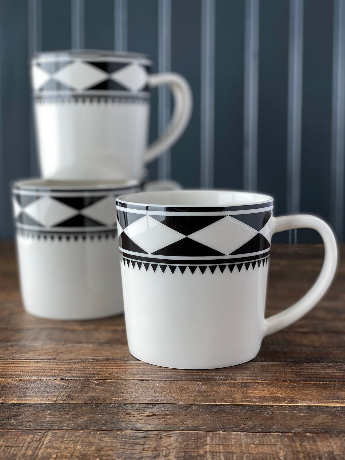 Front view of Fez Mug in Black showcasing black and white geometric pattern with matching mugs on a wood table