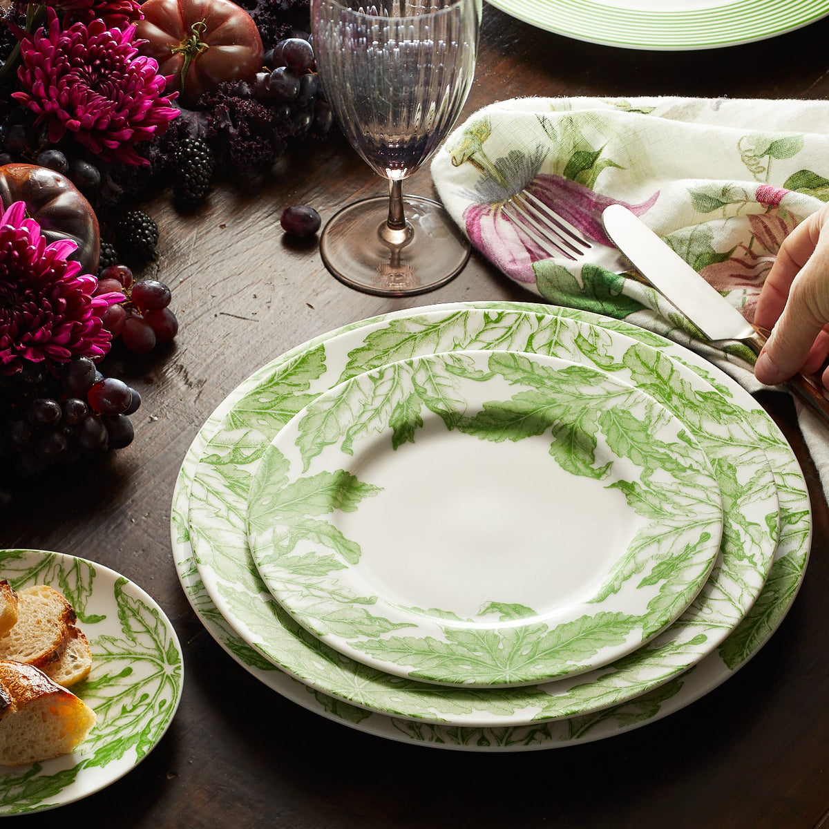 Overhead view of Freya Rimmed Dinner Plate showcasing green florals on creamy white porcelain with a table setting