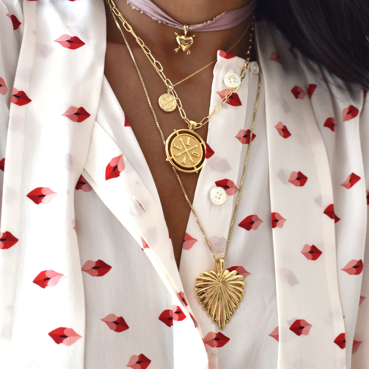 Close-up of Love Full-Heart Pendant Necklace showcasing a gold heart-shaped palm leaf pendant on a floral blouse