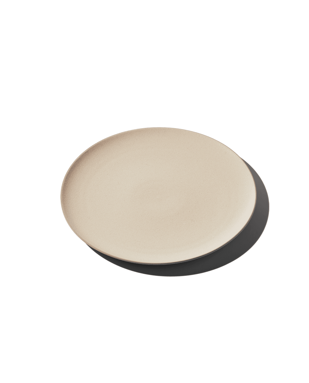 Angled top view of The Full Plate in dune beige showing shallow rim and matte ceramic finish on plain background with shadow