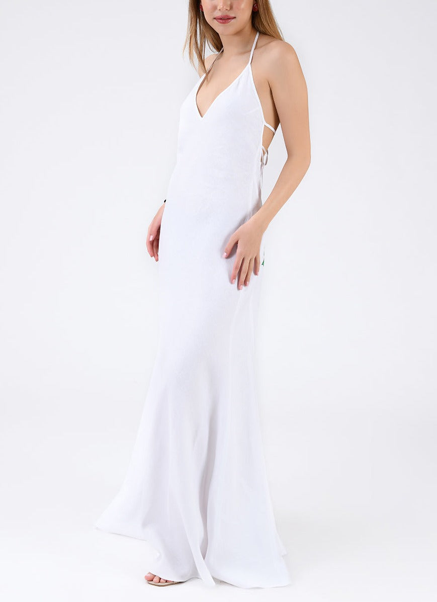 Three-quarter view of Saff Dress showcasing white linen halter with V-neck, low tie back, and flared full-length hem on model