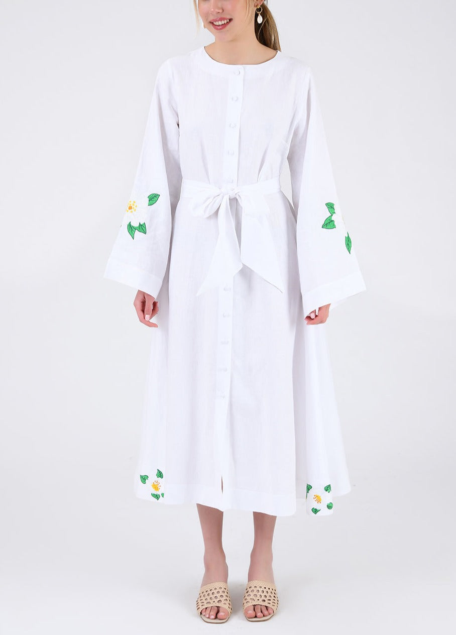 Front view of Jama Dress, white linen midi with button front, tie waist, and embroidered bell sleeves on plain background