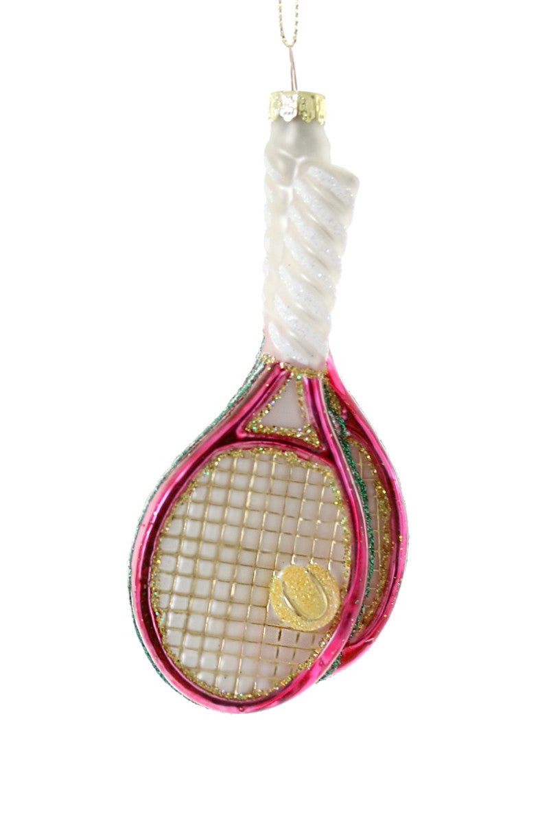 Front view of glass tennis racket ornament showing pink and gold glitter frame, twisted pearly white handle, and gold tennis ball on white background