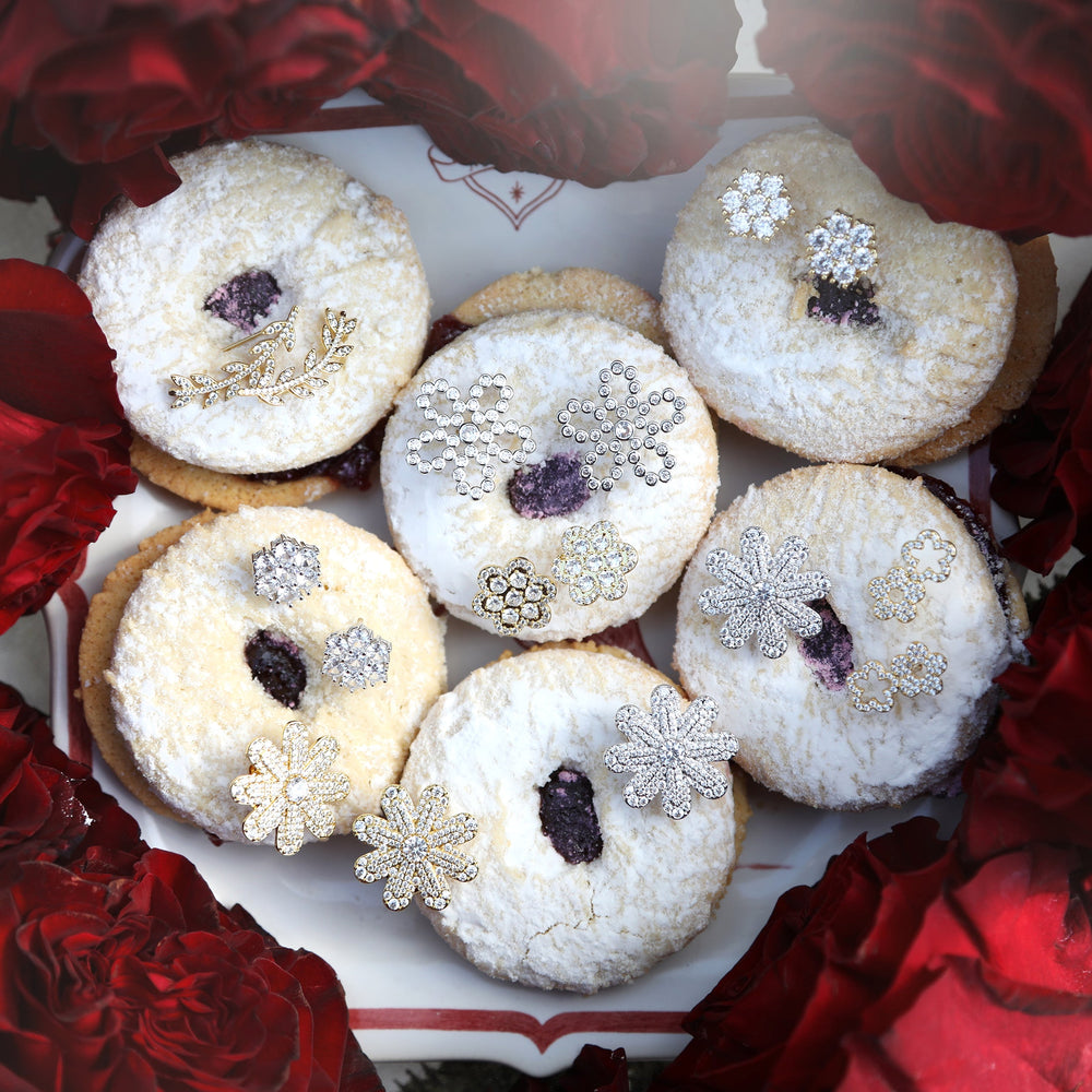 Close-up of Louisa stud earrings showcasing pavé CZ floral designs on powdered cookies surrounded by red roses