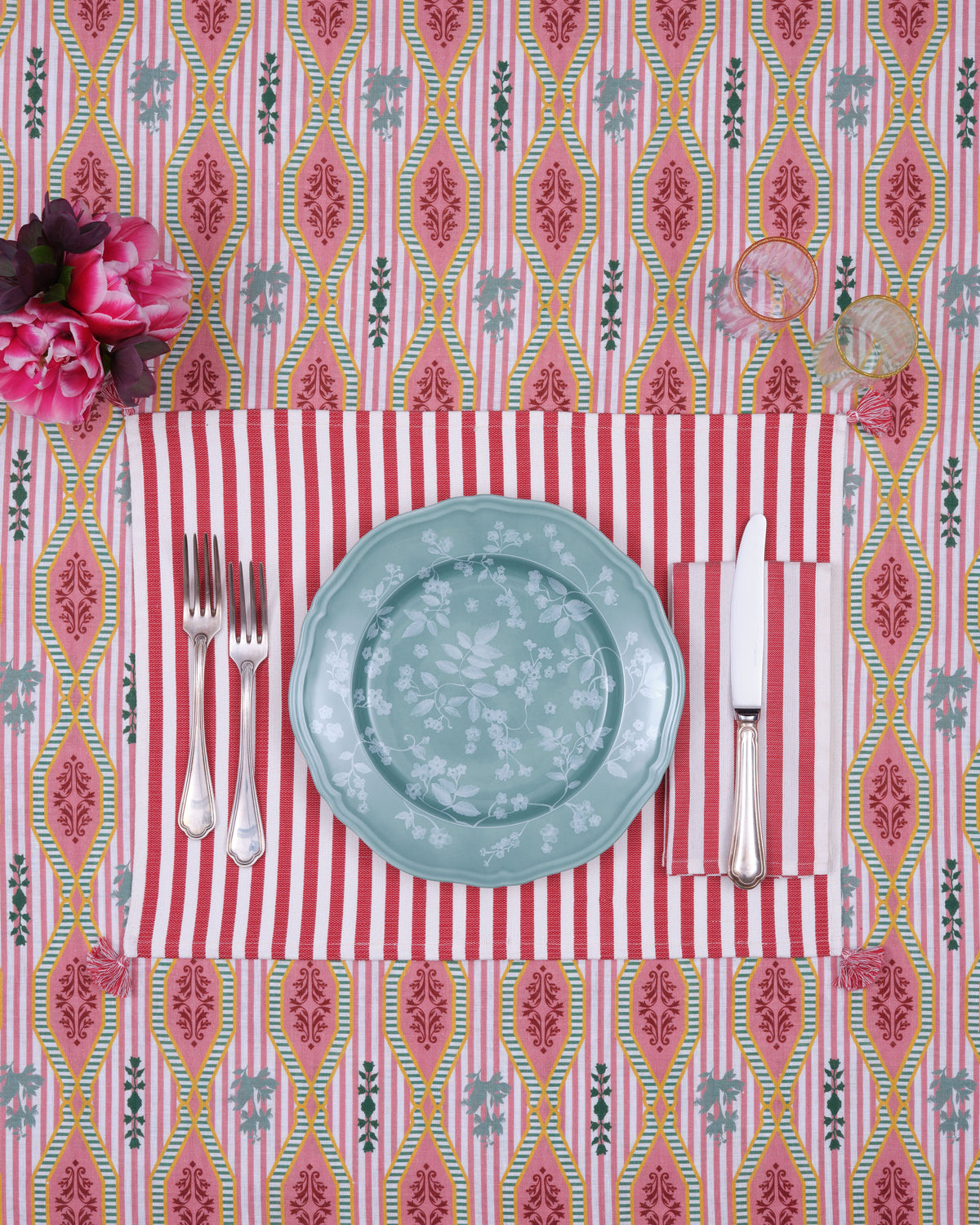 Vera Stripe Placemat in Red sets a table with a floral plate, silverware, flowers, and glasses