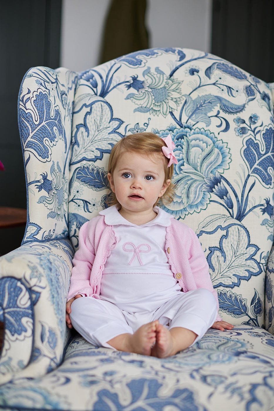 Front view of Bow Crochet Playsuit on toddler showing pink bow, peter pan collar and picot trim on blue floral chair