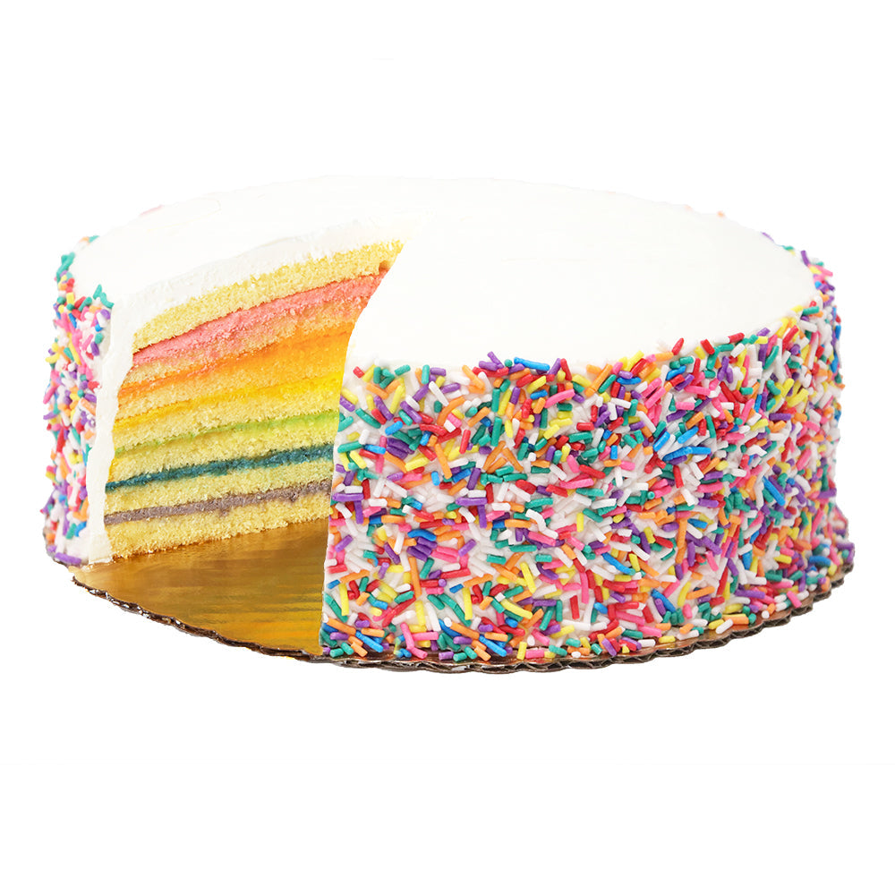 Side view of rainbow layer cake with white buttercream, sliced to show seven colorful layers, sides covered in sprinkles