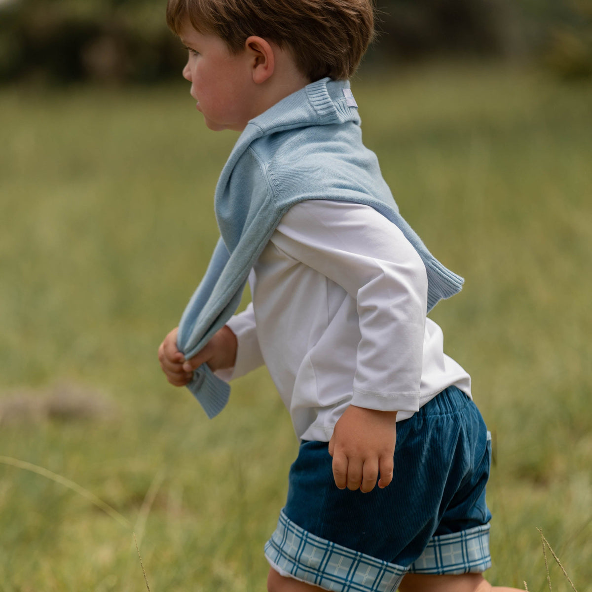 Side view of Long Sleeve Teddy Peter Pan in Classic White showing long sleeves and stretch fit on a toddler in a grassy field