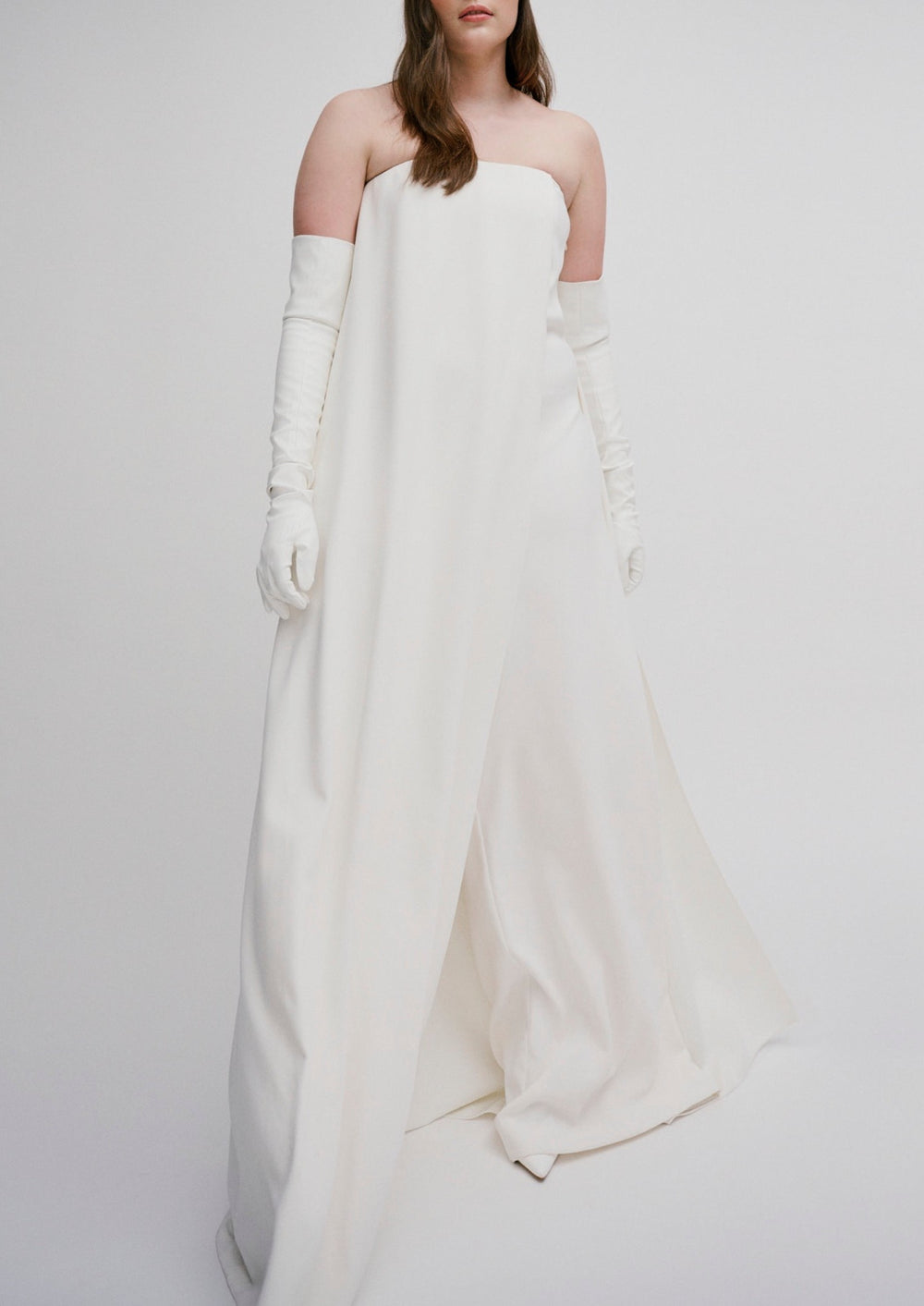 Front view of Marsanne Jumpsuit with strapless corset bodice, wide-leg trousers and draped cape on light gray background
