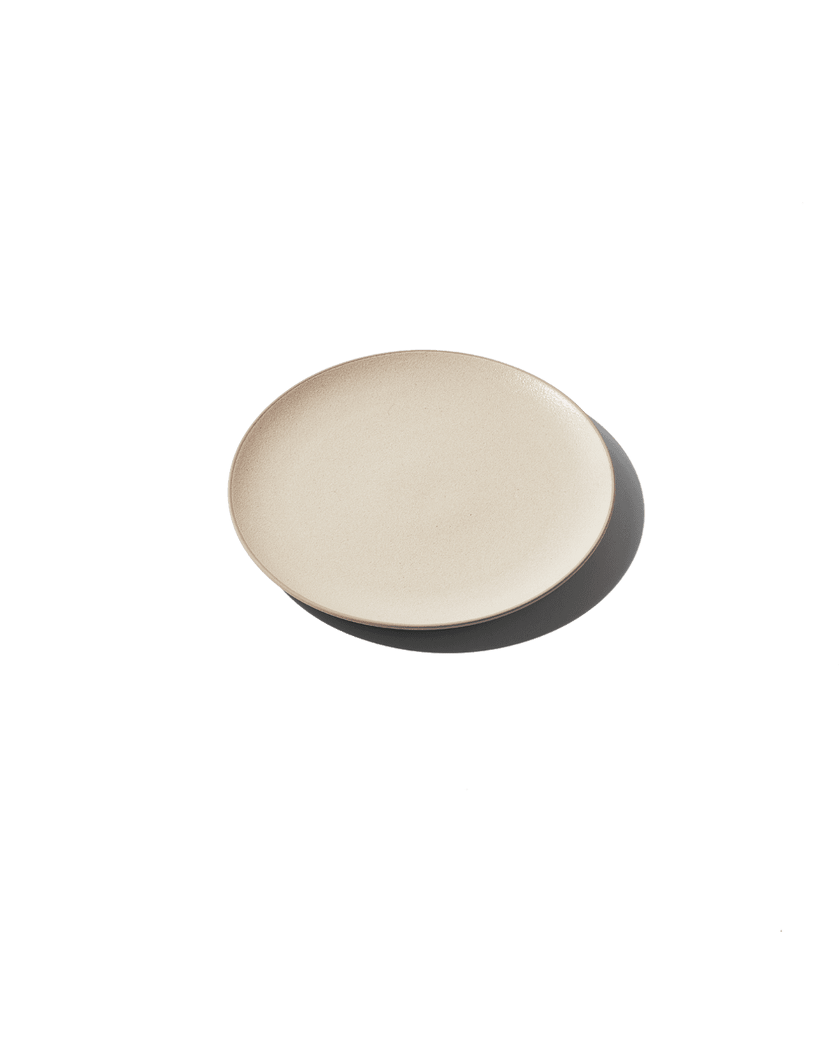 Angled view of The Half Plate showcasing hand-finished Korean clay with a plain green background