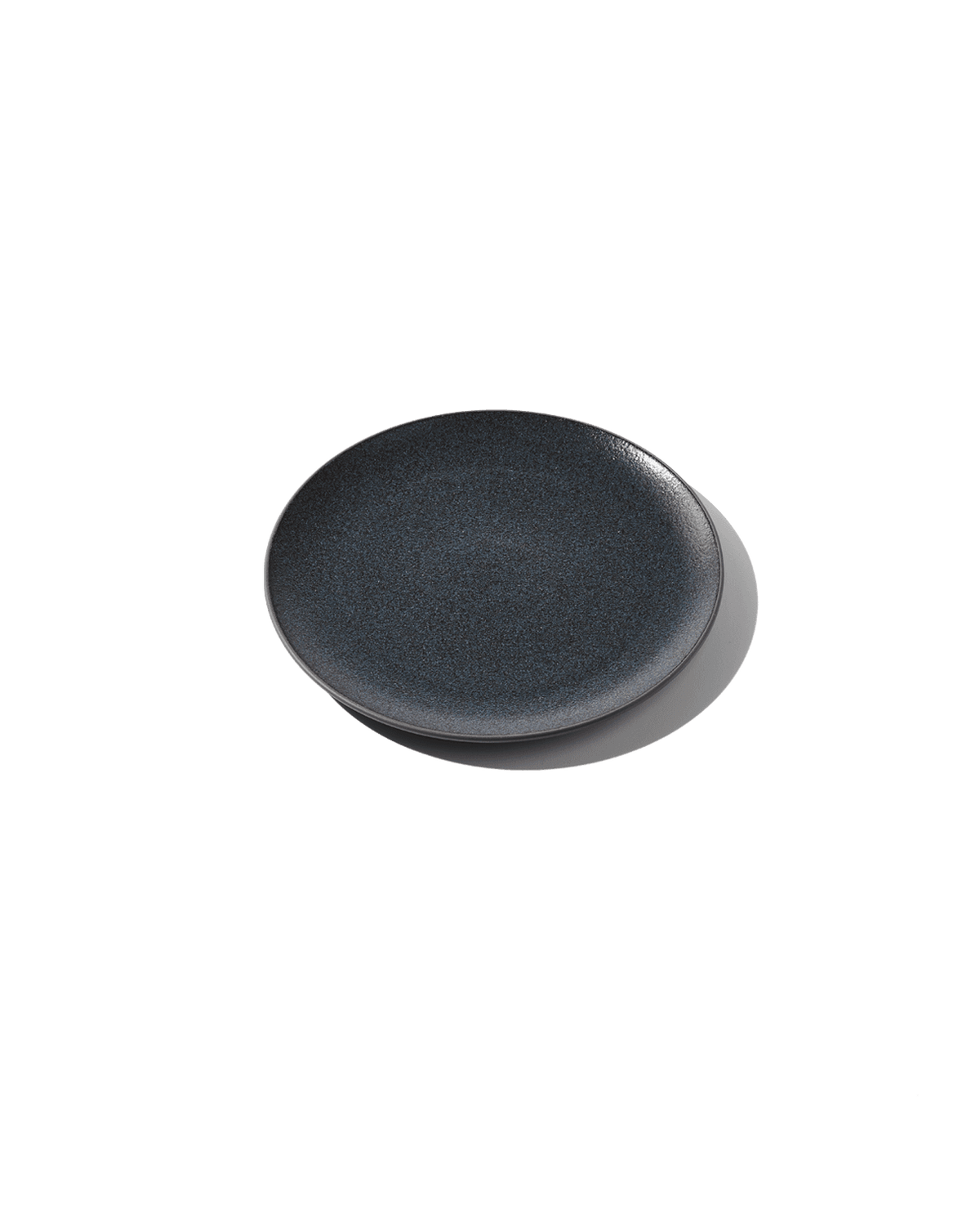 Angled view of The Half Plate showcasing its dark textured Korean clay surface with a plain green background