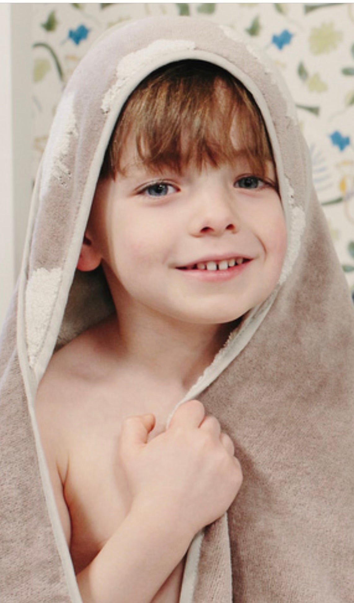Child smiling while wrapped in the hooded towel from the Sweet Sheep Jacquard Bath Set