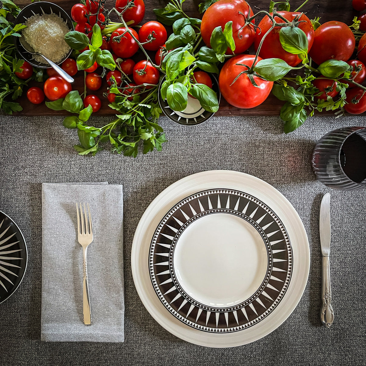 Marrakech dinnerware arranged with fresh tomatoes and herbs on a set dining table