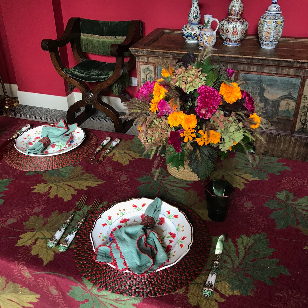 Two mint cotton napkins with red scalloped embroidery on a colorful table setting