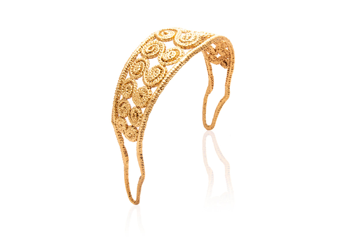 Front three-quarter view of the Spiral Headband showcasing spiral gold accents and Iraca palm leaf on a white background