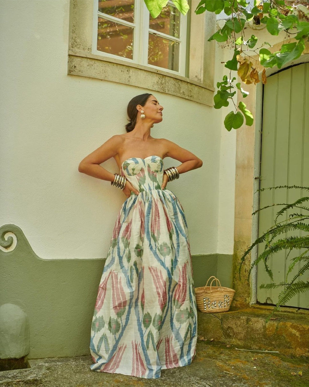 Full-length Tulip Dress, strapless corset bodice, cinched waist and gathered multicolor ikat silk skirt against stucco wall