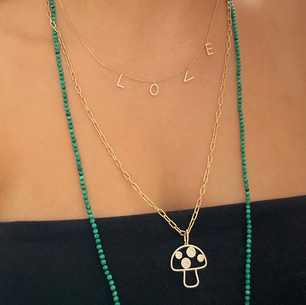 Close-up of Separated Love Text Necklace showcasing a gold chain with diamond-studded letter charms spelling LOVE, layered on a model wearing a black top
