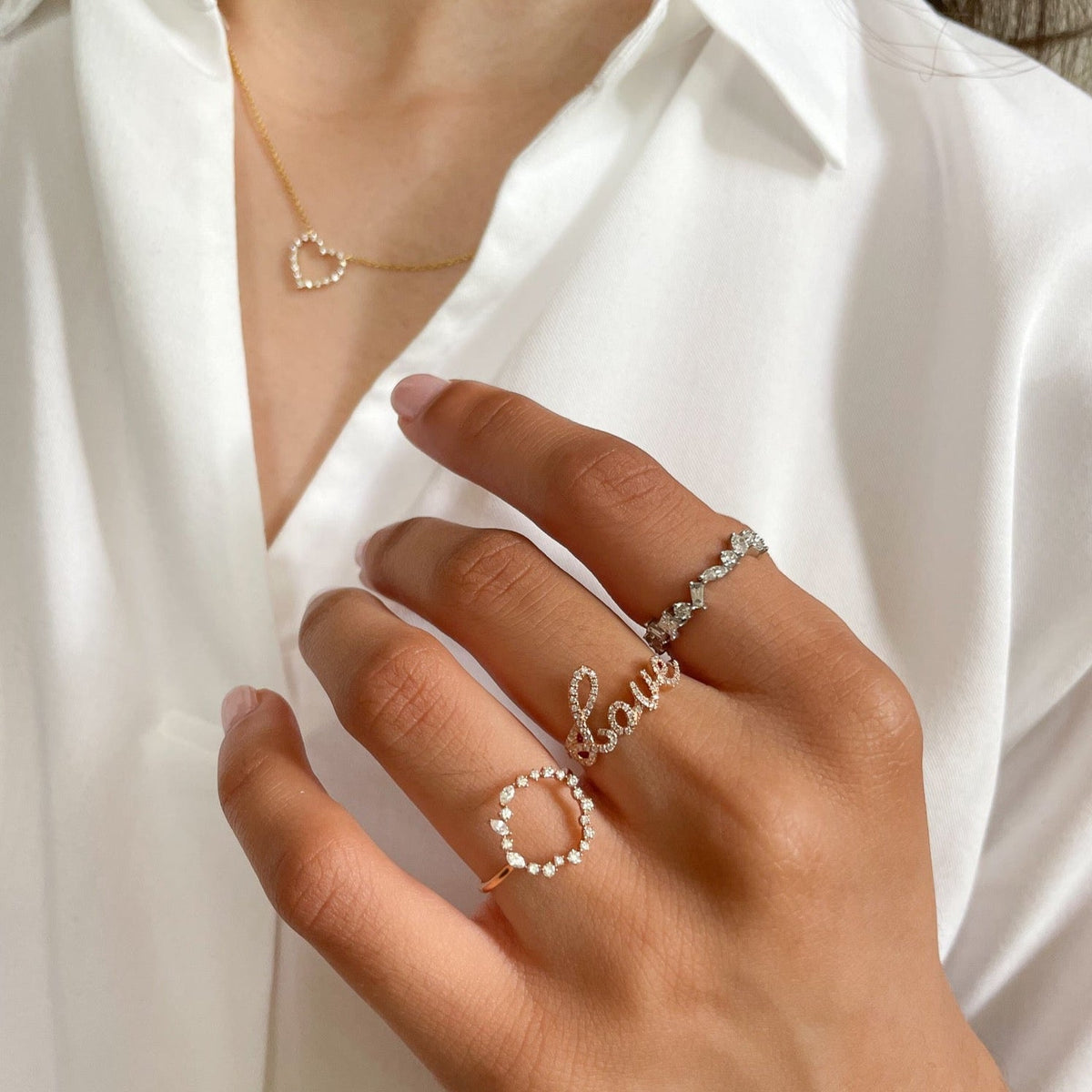 Close-up of Classic Love Ring on model’s finger showcasing ‘love’ script formed by cubic zirconia with white shirt background